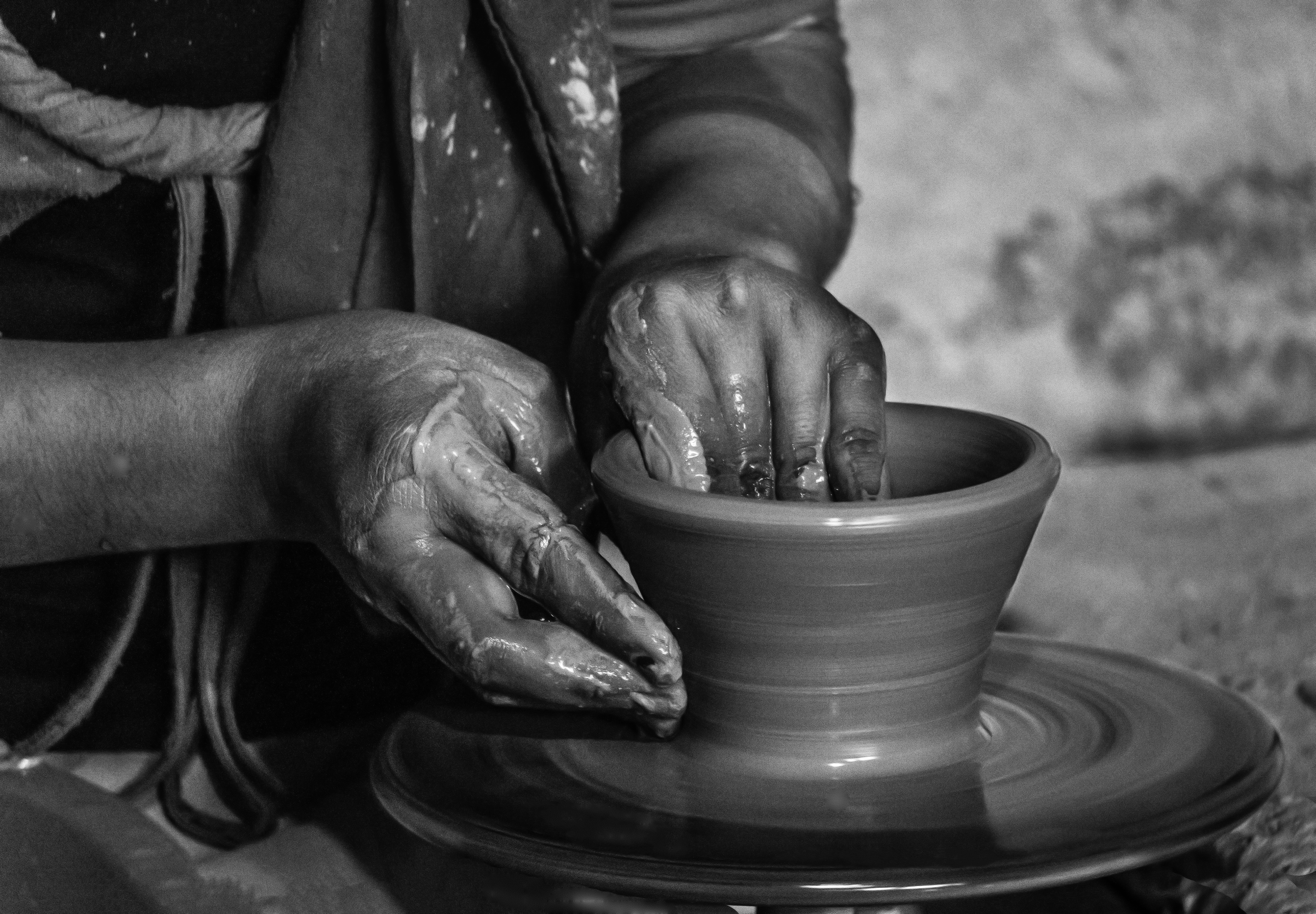 Close-up of hands carefully shaping a small clay vessel